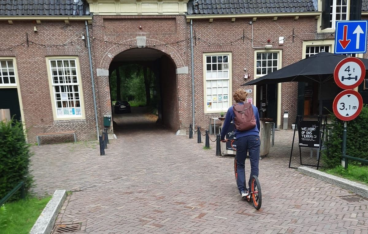 Someone riding a rented kickbike through an old city gate in Utrecht